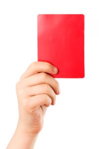 Red card in a hand in front of a white background