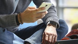 A Google employee wears an LG G Android Wear smart watch while using his phone at the Google I/O developers conference in San Francisco June 26, 2014. The LG G watch was announced along with the Samsung Gear Live during the conference keynote. REUTERS/Elijah Nouvelage (UNITED STATES - Tags: BUSINESS SCIENCE TECHNOLOGY)